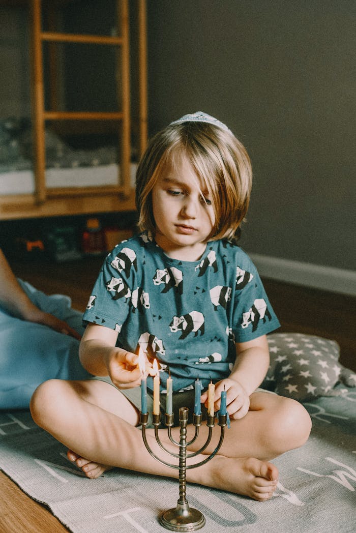 brand-01 Young child lighting a menorah for Hanukkah celebration indoors, emphasizing Jewish culture and tradition.
