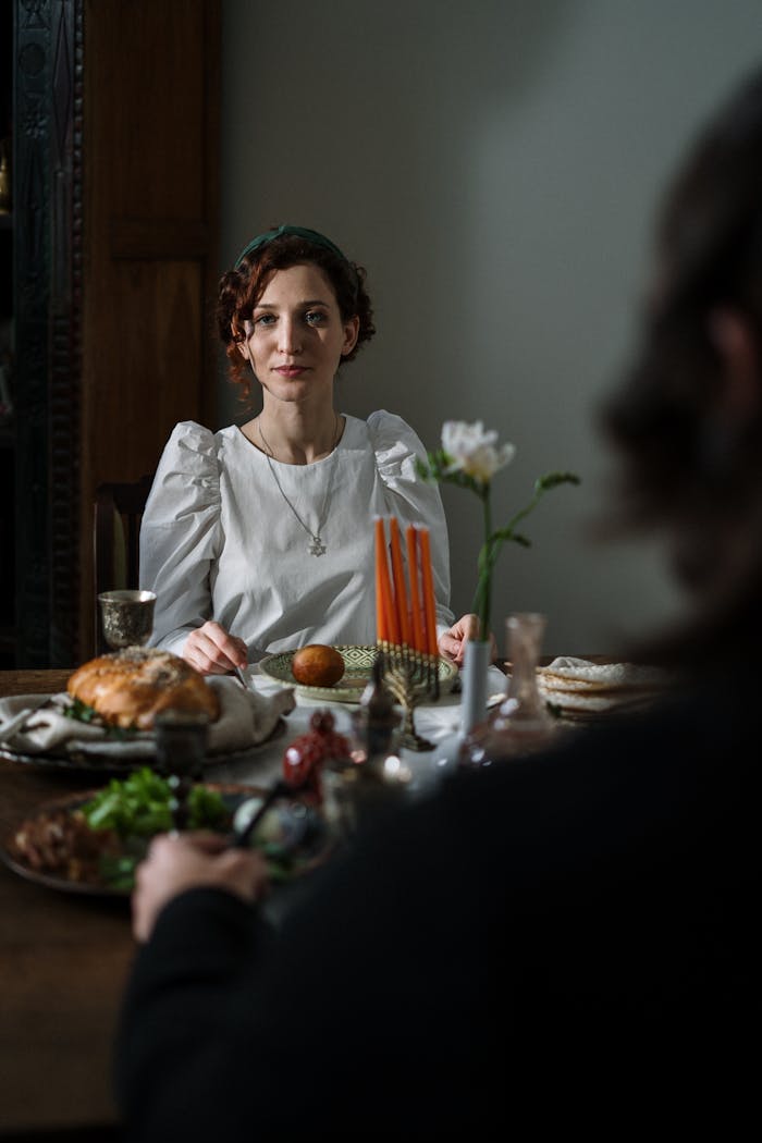 brand-03 A cozy indoor scene of a Jewish woman enjoying a Shabbat meal with traditional food and candles.