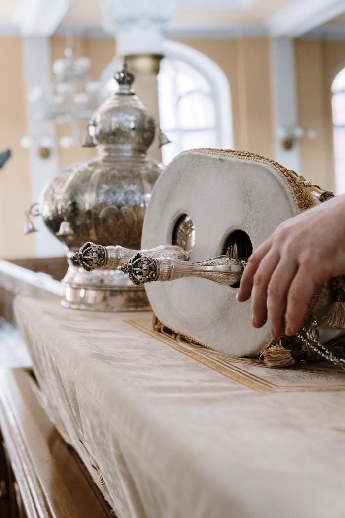 A detailed view of a Torah scroll being handled inside a synagogue, showcasing intricate religious artifacts.